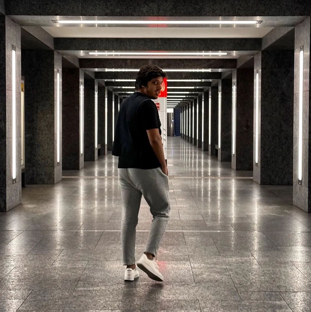Hassan glancing back in a long, symmetrical lit corridor