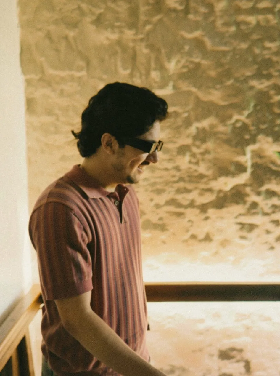 Hassan in a striped polo and sunglasses, smiling, in warm light