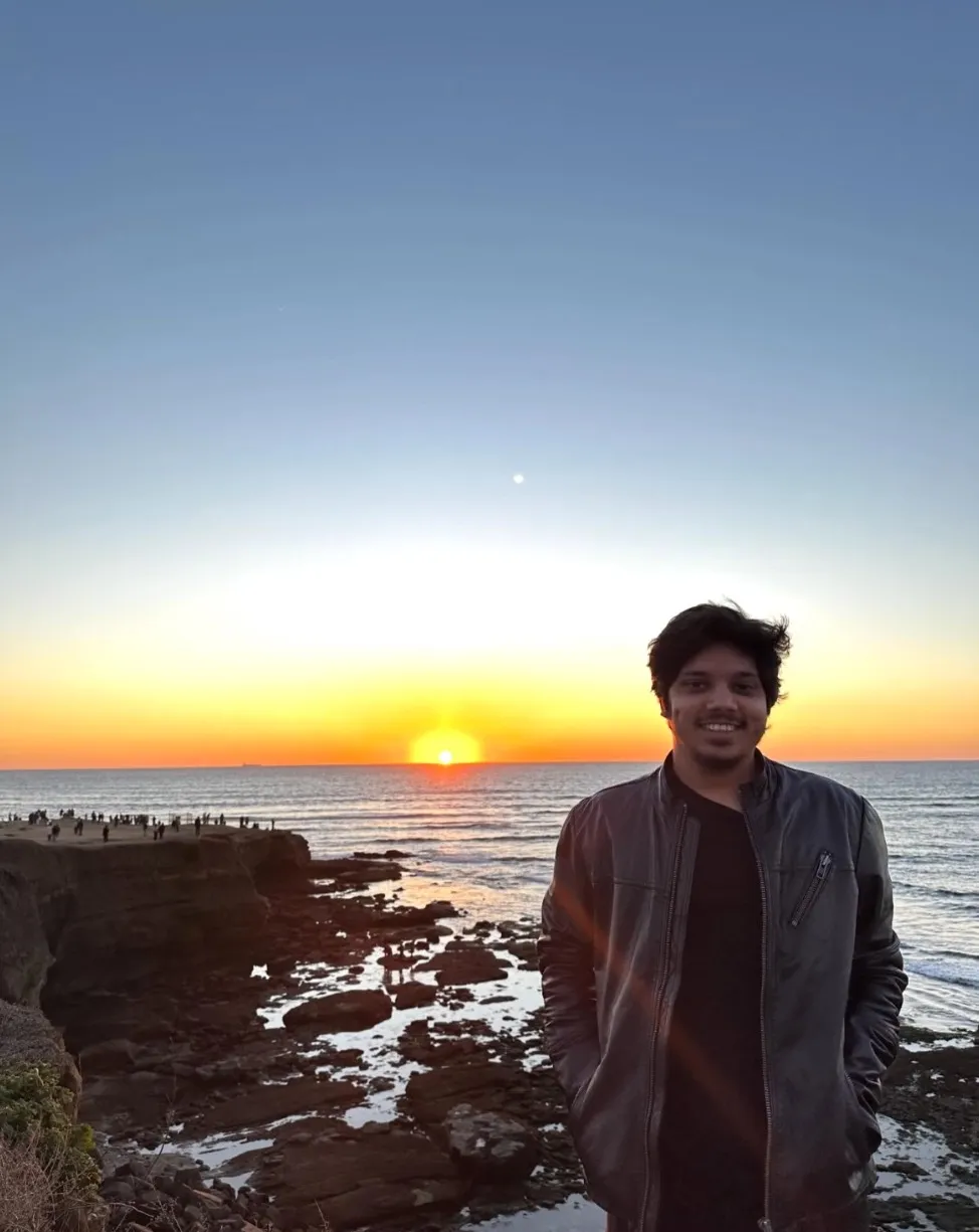 Hassan smiling on the cliffs as the sun sets over the Pacific